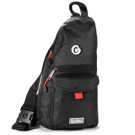 Black nylon traveler sling bag with orange zipper pulls and a red accent tab. Features a "Cookies" logo patch and a circular "C" logo.