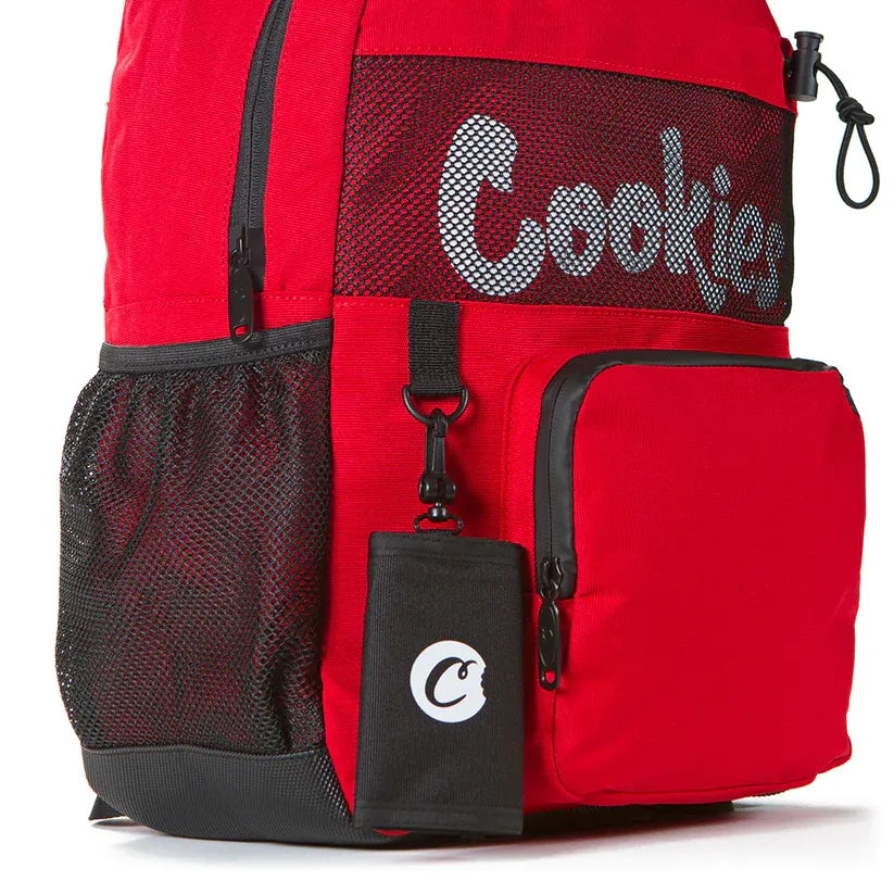 Red Stasher smell proof backpack with black mesh side pockets and a black pouch with the Cookies logo attached to the front.