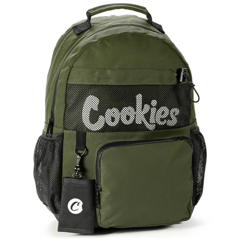 Olive green Stasher smell proof backpack with white "Cookies" logo across the front mesh panel, side mesh pockets, and a front zippered pocket. Includes a detachable "Cookies" coin pouch.
