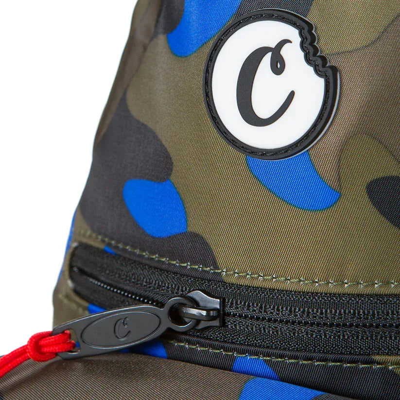 Traveler smell proof sling bag in camouflage print with blue and black accents, featuring a black zipper and red pull cord.