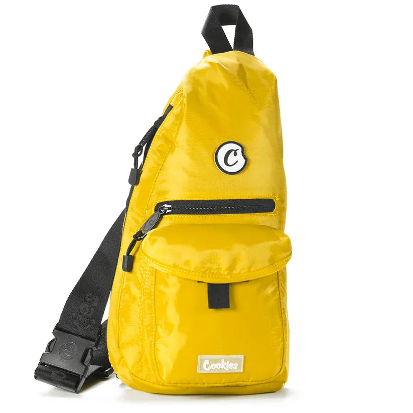Yellow nylon traveler sling bag with black strap, front zipper pocket, and flap pocket with "Cookies" logo.